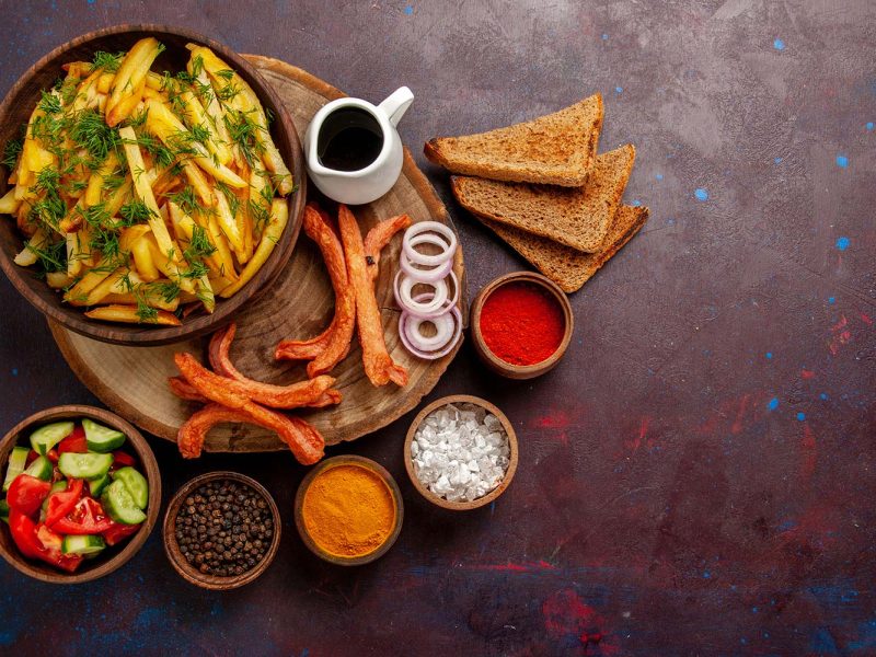 top-view-fried-potatoes-with-seasonings-bread-loafs-different-vegetables-dark-desk